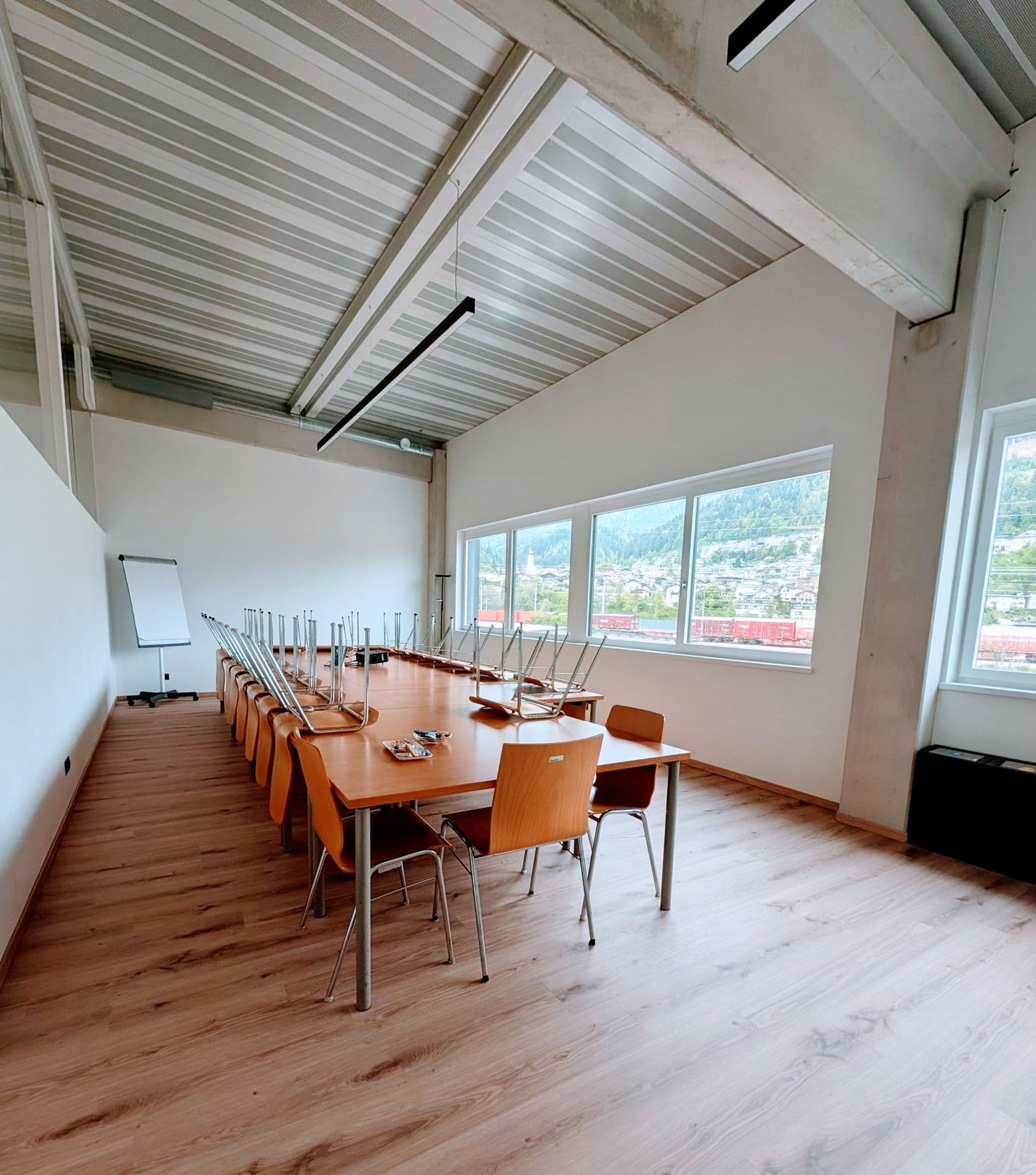 Bildungsraum im pgz Fritzens mit langer Tafel, Stühlen, Flipchart und großen Fenstern mit Blick auf Fritzens und die Berge