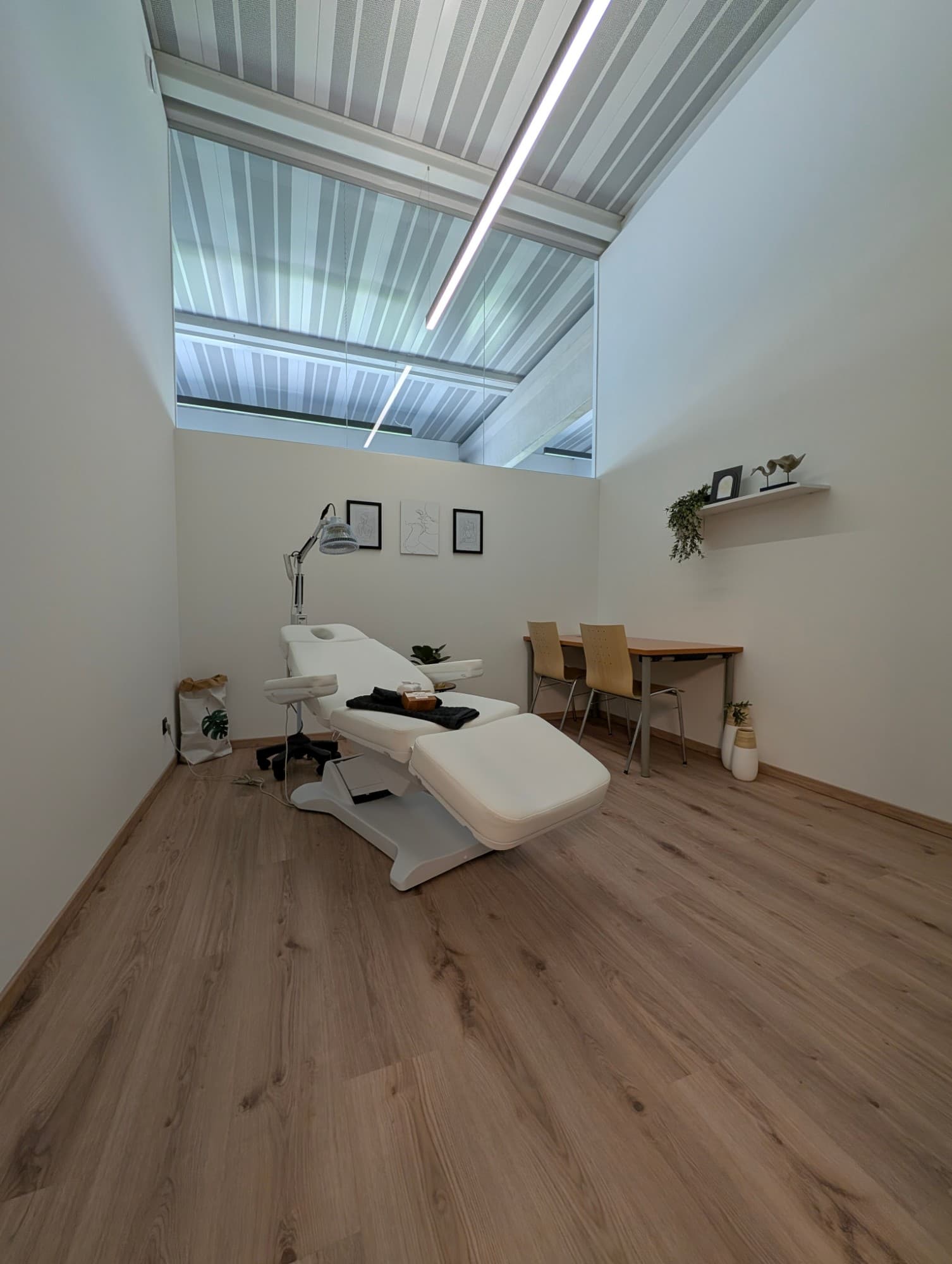 Praxis Karll mit Behandlungsliege, Wärmelampe, Tisch mit zwei Stühlen und Oberlicht